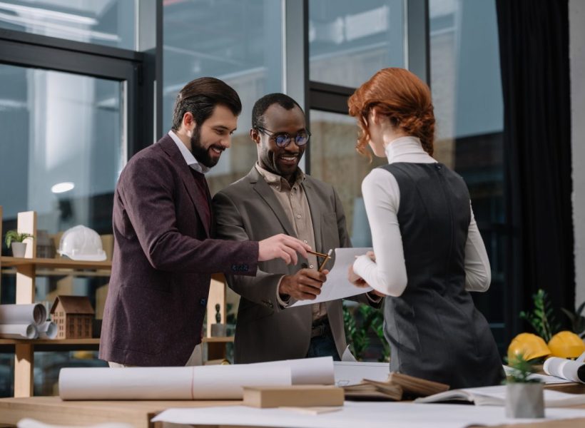 happy-multiethnic-team-of-architects-discussing-documets-at-office.jpg